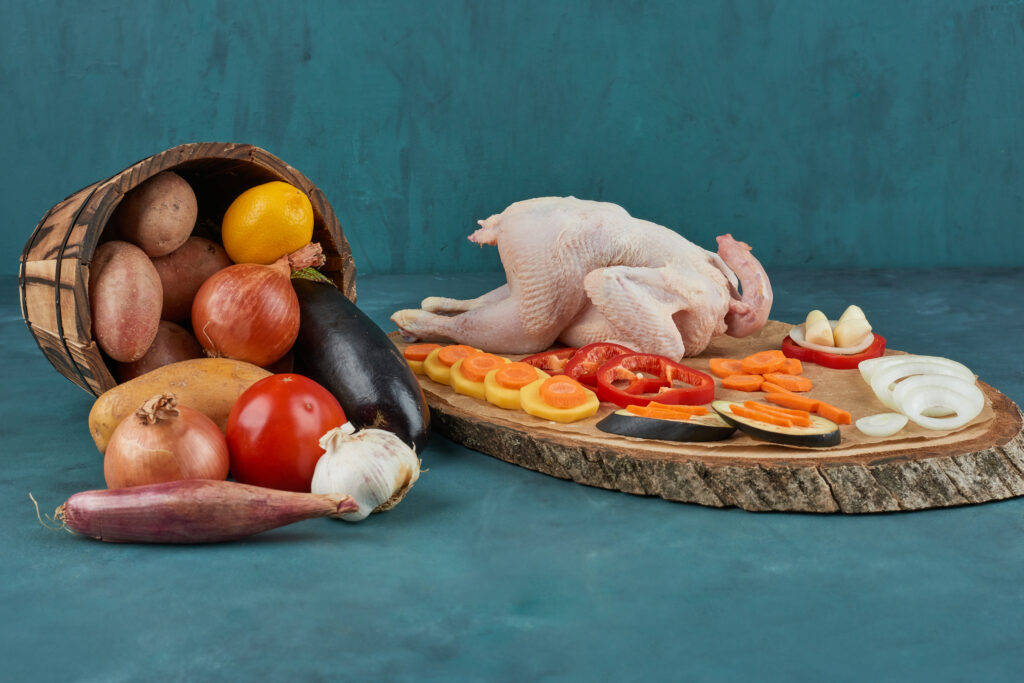 chicken on a wooden board with vegetables in the bucket